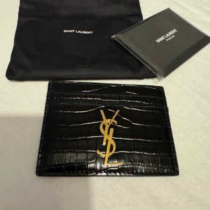 Saint Laurent crocodile leather korthållare  - Helt sprillans ny ysl korthållare, digitalt kvitto medföljer samt allt som man fick med som är med på bilderna. Helt oanvänd helt ny. Ny pris på denna ligger på runt 3200kr… mitt pris 1700kr! Först till kvarn som gäller.