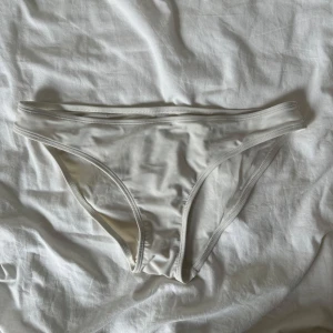 Vita bikiniunderdelar i enkel designi - Snygga vita bikiniunderdelar med klassisk passform och stilren look. Modellen har smala kanter för en clean och tidlös känsla. Perfekt för strandhäng eller poolparty. Materialet känns mjukt och följsamt mot huden