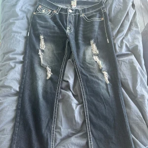 True Religion Billy Supert jeans, blå - Om du är rädd för att dom är stora kan jag rekommendera ett skärp👍. Säljer ett par blå True Religion Billy Supert bootcut jeans med slitna detaljer och kraftiga kontrastsömmar riktigt billigt. Jeansen har klassiska bakfickor med logga och är tillverkade i denim. Perfekta för dig som gillar streetwear och vill sticka ut. *Pris kan diskuteras vid snabbt köp, kan även mötas upp i Stockholm*