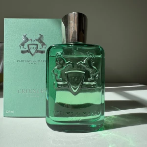 Parfums de Marly Greenley EdP 125ml - Greenley från Parfums de Marly är en lyxig parfym i en stilren, grön glasflaska med silverdetaljer och graverad logga med två hästar. Flaskan rymmer 125 ml och har en tung, metallisk kork med märkets emblem. Doften är fräsch och påminner mycket om citrus, gröna äpplen och naturen! Helt suverän till vår/sommar/höst                        Nypris är 3 055 kr (Åhléns) Använt enligt bild 