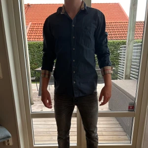 Mörkblå skjorta från Burberry - Snygg mörkblå skjorta från Burberry. Eftertraktad modell. Självklart äkta. Väldigt bra skick, inga defekter. Storlek L men sitter mer som M. Priset är ej hugget i sten men snabba affärer kommer prioriteras. Hör gärna av er vid minsta lilla fundering 🫶🏻