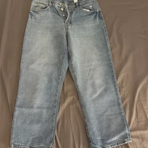  Ljusblå raka jeans - Klassiska jeans i ljusblå tvätt med raka ben och knappgylf. Jeansen har fem fickor och en avslappnad passform, perfekta för en chill och tidlös look. Tillverkade i slitstarkt bomullsjeansmaterial.