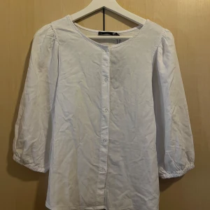 Tunn vit blus  - En vit söt blus i lätt och tunt material. Ärmarna går till ungefär vid armbågen och är ganska vida. Den är även lite puffiga vid axlarna. Passformen är avslappnad och bekväm, perfekt för varma dagar. Etiketten finns även kvar då den är i nytt skick, själv har jag bara provat på den.