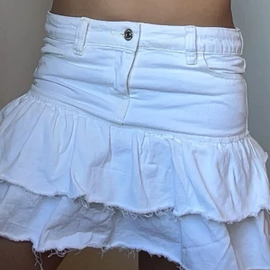 Vit volangkjol från Gina Tricot - Supersöt vit jeanskjol från Gina med volanger. Helt oanvänd men har ej prislapp kvar. Inga fläckar eller andra defekter, säljer då den ej kommer till användning. Nypris 300kr säljer för 240kr till och börja med🥰