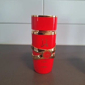 Yara Candy parfym från Lattafa - Yara Candy från Lattafa är en parfym i en snygg röd flaska med guldiga detaljer och arabiska tecken. Doften har tydliga inslag av vanilj, frukt, pudriga toner, vit blomma och citrus. Flaskan är tillverkad i plast med metalliska accenter och har en modern, unik form. Ca 70 ml kvar