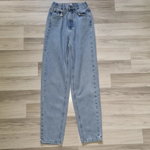 Ljusblå jeans från Pull&Bear, strl 32 - Säljer ett par ljusblå jeans från Pull&Bear i storlek 32. Modellen har hög midja, raka ben och klassiska fem fickor. Jeansen är tillverkade i bomull och har bälteshällor samt knapp- och dragkedjestängning. Perfekta för en avslappnad och trendig look.