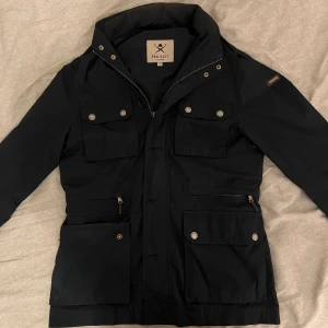 Hacket London Field  Jacket - Säljer denna  snygga field jacket från Hackett London. Perfekt för vår och sommar. Jackan är i bra skick, förutom ett litet hål vid ärmen. (Se sista bilden). Hör gärna av dig om du har frågor eller vill ha fler bilder. 