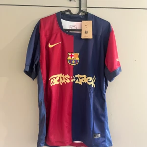 FC Barcelona fotbollströja Raphinha 11 - Säljer en officiell FC Barcelona matchtröja från Nike med Raphinha 11 på ryggen. Tröjan är röd och blå med klubbmärke på bröstet och gult Nike-märke. Tryck i gult och vitt framtill och baktill. Kortärmad modell, perfekt för fotbollsfans.