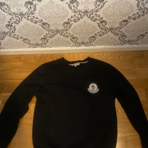 Svart sweatshirt från Moncler - Säljer en svart sweatshirt från Moncler med rund halsringning och Moncler-logga på bröstet. Tröjan har en klassisk passform och är tillverkad i mjukt bomullsmaterial. Perfekt för en stilren och avslappnad look. Pris går att diskuteras!