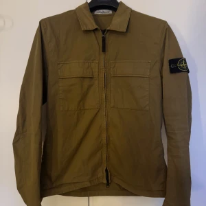 Olivgrön overshirt från Stone Island - Säljer en overshirt från Stone Island med klassisk patch på ärmen. Sparsamt använd och har inga defekter eller skador. Har kvitto från beställning på NK. Hör av er vid frågor! Kan diskutera pris vid snabb affär