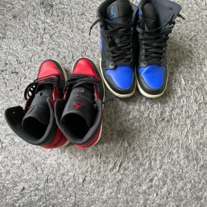 Nike Air Jordans i svart, rött och blått - Säljer två par Nike Air Jordans high-top sneakers. Ena paret är svart och rött med vit sula, det andra är svart och blått med vit sula. Skick 8/10. Går även köpas separat för 500kr styck! Röda strl 44, Blåa strl 45,5 men båda passar 44/45