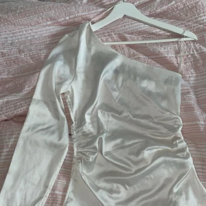Vit silk blus med en arm  - Vit Silke blus  Storlek Xs utan prislapp har aldrig haft på mig den. Har en dragkedja på sidan. Från bikbok 