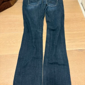   jeans  - Mörkblå jeansbyxor med bootcut passform och fickor bak med broderad detalj. Byxorna har låg midja och lätt slitning framtill för en cool look. Dem är perfekta och fått mycket kärlek men har blivit förmå. Storlek s/xs