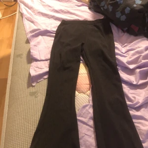Svarta ribbade bootcut byxor - Säljer ett par svarta ribbade byxor med bootcut-modell. Byxorna har hög midja och är stretchiga, perfekta för en trendig och bekväm look. Passar till många olika stilar och är lätta att matcha med olika toppar.