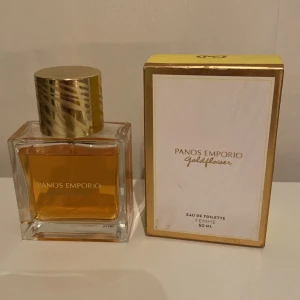 Panos Emporio Goldflower Eau de Toilette 50 ml - En elegant parfym med namnet Goldflower från Panos Emporio. Flaskan är fyrkantig i genomskinligt glas med guldig vätska och ett stilrent guldlock. Förpackningen är vit med gulddetaljer och rymmer 50 ml Eau de Toilette för kvinnor.
