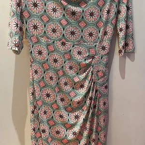 Mönstrad klänning från Ilse Jacobsen - Säljer en färgglad klänning från Ilse Jacobsen i stl S med geometriskt mönster i rosa, mintgrönt och vitt. Klänningen har trekvartsärm och en lätt draperad halsringning. Perfekt för dig som gillar unika prints och bekväm passform. Helt ny! 