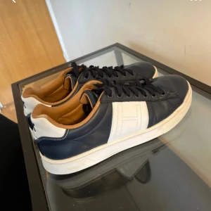 Marinblå sneakers från Hackett - Snygga marinblå sneakers från Hackett, Perfekta för en stilren vardagslook. De är i väldigt fint skick, nypris = 2200 kr mitt = 199 kr, skriv om minsta lilla fundering!
