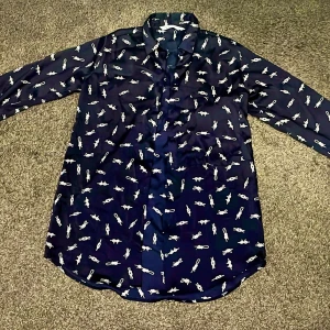 Mörkblå skjorta med vitt mönster - Zara Snygg mörkblå skjorta med vita små figurer som mönster. Skjortan har långa ärmar och klassisk krage, perfekt för dig som vill sticka ut lite extra. Knappar framtill och rundad nederkant! 👔
