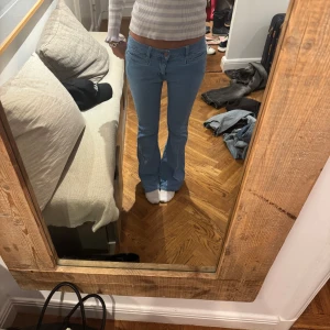 Ljusblå bootcut jeans - Säljer ett par ljusblå jeans med bootcut passform och låg midja. Klassisk femficksmodell med dragkedja och knapp framtill. Perfekta till vardags för en avslappnad men trendig look.