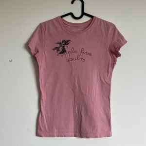 Rosa t-shirt med tryck och broderi - Söt rosa t-shirt från triple five soul med korta ärmar. Framsidan har ett broderat motiv av en ängel och med små hjärtan. T-shirten har en klassisk passform och är gjord i mjuk bomull. Från tidig 00-tal