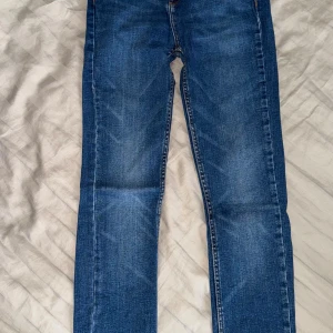 Blå jeansbyxor från Zara - Klassiska blå jeansbyxor från Zara med normal passform. Byxorna har dragkedja och knapp framtill samt fem fickor. Perfekta till vardags och enkla att matcha med olika toppar.