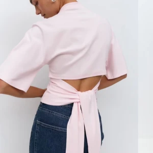 Ljusrosa omlottopp med knytband - Säljer en ljusrosa omlottopp med korta ärmar och snygg knytning i ryggen. Toppen har öppen rygg och breda knytband som ger en trendig look. Perfekt att styla med jeans eller kjol, från gina tricot😍