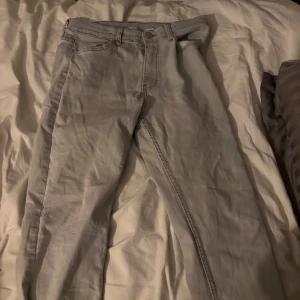 Ljusgrå jeansbyxor - Säljer ett par ljusgrå jeansbyxor med klassisk femficksdesign och raka ben. Byxorna har normal passform och stängs med dragkedja och knapp i midjan. Perfekta till vardags för en clean och enkel stil.