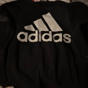 Svart sweatshirt från Adidas - Säljer en svart sweatshirt från Adidas med stor vit logga på bröstet. Tröjan har rund hals och långa ärmar. Perfekt för en sportig och avslappnad stil. Klassisk design med bekväm passform. Den är i storlek S.