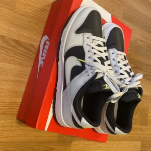Nike Dunk Low Grey Panda Volt - Säljer ett par Nike Dunk Low i färgen Grey Panda Volt, endast använda en gång – i princip nyskick! Klassisk svart/vit/grå design med neon-detaljer som sticker ut. Äkta, går att scanna qr koden i skorna och på lådan. Lådan följer med. Köpta för 2500kr