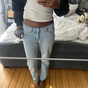 Ljusblå raka jeans  - Säljer ett par klassiska ljusblå jeans från Levis med rak passform och normal midja. Jeansen har fem fickor, orange sömmar och knappgylf. Perfekta till vardags för en avslappnad stil.