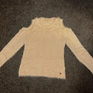 Beige fluffig tröja med cut out-detaljer - Säljer en supermjuk och fluffig beige tröja med långa ärmar och trendiga cut out-detaljer vid axlarna. Perfekt för dig som vill ha något både snyggt och bekvämt! Liten logo nertill.🤎🫶🏻💛