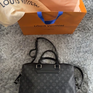 Louis Vuitton *KVITTO Odyssey Briefcase Canvas  - Kvitto medföljer! Säljer en svart axelväska från Louis Vuitton med klassiskt monogrammönster. Väskan har både handtag och justerbar axelrem, silverfärgade metalldetaljer och dragkedja. Tillverkad i skinn och har märkning på insidan. två flaws finns bilder får man vid förfrågan!