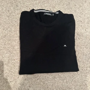 Svart stickad tröja från J.Lindeberg - Säljer en svart stickad tröja från J.Lindeberg med rund halsringning och diskret logga på bröstet. Perfekt för lager-på-lager och enkel att matcha med det mesta. Aldrig använd bara testad på nypris 1600 mitt pris 650