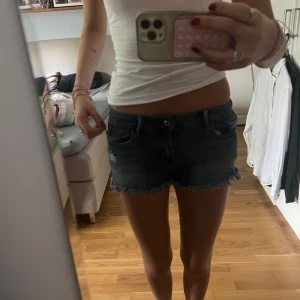 Lågmidjade mörkblå jeansshorts  - Säljer ett par lågmidjade mörkblå jeansshorts med fransig kant nertill. Klassisk femficksmodell och låg midja. Perfekta för varma dagar och enkel att matcha med olika toppar. Aldrig andvänt ❣️