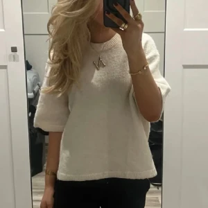 Vit stickad tröja med kort ärm - Säljer en enkel och stilren vit stickad tröja med korta ärmar och rund halsringning. Perfekt att matcha med jeans eller kjol. Tröjan har en mjuk och bekväm känsla. 