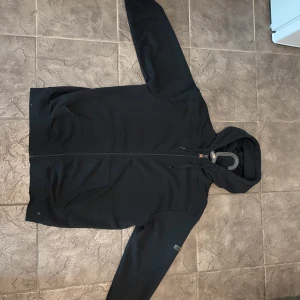 Ellesse zip hoodie  - Säljer en svart hoodie från Ellesse i storlek M med dragkedja framtill och två fickor. Tröjan har huva med snörning och en diskret logga på ärmen. Perfekt för en avslappnad stil och enkel att matcha med det mesta. Mycket bra skick 