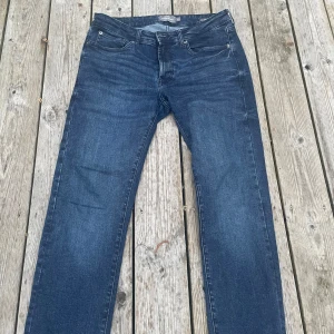 Mörkblå jeansbyxor från Dressmann - Säljer ett par mörkblå jeansbyxor från Dressmann i modellen slim fit. Klassisk femficksdesign med dragkedja och knapp framtill. Jeansen har raka ben och är tillverkade i ett mjukt denimtyg som passar till många olika stilar. Hör av dig vid frågor 😊