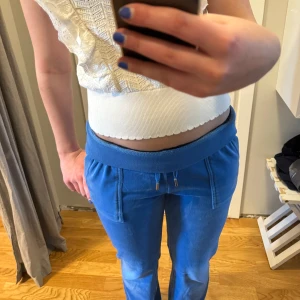 Blå mjukisbyxor från Juicy Couture - Säljer ett par juicy couture mjukisar i blå, de är använda några gånger så som man kan se så har de tappat lite färg på knäna. Ena metallgrejen på snöret har ramlat av en gång men har limmat på den hyfsat. Säljer för att de har blivit för korta för mig 😇