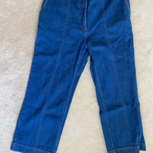 Blå jeansbyxor från Baum und Pferdgarten - Säljer ett par nya blå jeansbyxor från Baum und Pferdgarten med raka ben och hög midja. Byxorna har synliga sömmar framtill och klassisk jeanslook. Perfekta för dig som gillar en stilren och avslappnad vibe.