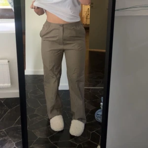 Beiga raka chinos med fickor - Snygga beiga chinos med raka ben och normal passform. Byxorna har sidfickor fram och fickor med knapp bak. Materialet känns lätt och skönt mot huden.