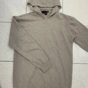 Beige hoodie från Oscar Jacobson - Säljer en stilren beige hoodie Storlek:S från Oscar Jacobson i mjukt material. Perfekt för en avslappnad och snygg look, perfekt till sommaren . Använd varsamt och fåtal gånger. 