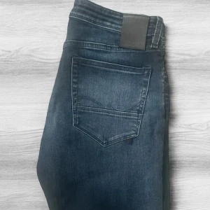 Mörkblå jeans från Jack & Jones - Snygga mörkblå jeans från Jack & Jones. Jeansen är perfekta för en avslappnad och stilren vibe. De är i modellen Slim/Glenn vilket ger en ”grisch” look som passar till stilrena skjortor men även avslappnade outfits såsom vanliga T-shirts. Storlek 33/32 i väldigt bra skick. Hör av dig vid funderingar, priset kan diskuteras vid snabb affär✅