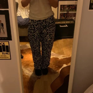 Svarta byxor med vit zebra-mönster - Unika svarta byxor från Polar Skate Co med vit zebra-inspirerat mönster och en liten broderad figur vid fickan. Byxorna har baggy passform och normal midja. 