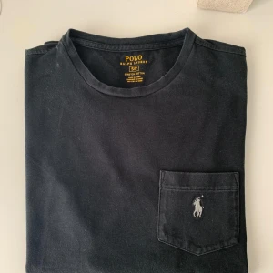 Svart t-shirt från Polo Ralph Lauren - Svart t-shirt från Polo Ralph Lauren med bröstficka, storlek S. Tröjan är i bra skick, skriv om ni har frågor!