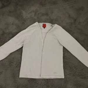 Ljusgrå kofta från JDY - Säljer en ljusgrå glittrig kofta från JDY i storlek M. Koftan har långa ärmar, knappar framtill och är tillverkad i ett mjukt, lätt glittrigt material. Perfekt att slänga över en topp för en enkel och stilren look.