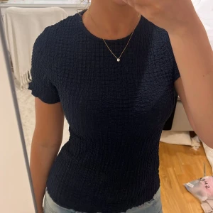 Mörkblå ribbad T-shirt - Säljer en mörkblå T-shirt med ribbat material och korta ärmar.passar perfekt till alla tillfällen. Använd fåtalgånger, väldigt bra skick! 