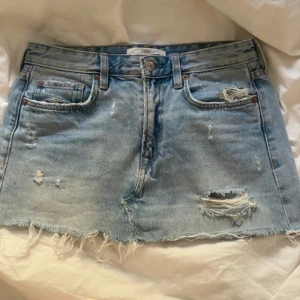 Ljusblå jeanskjol med slitningar - Säljer en ljusblå jeanskjol med rå kant och slitna detaljer. Jätte fin kjol som är perfekt nu för sommaren men som tyvärr är för stor för mig💕💕storlek 36 men skulle även säga att den passar 34