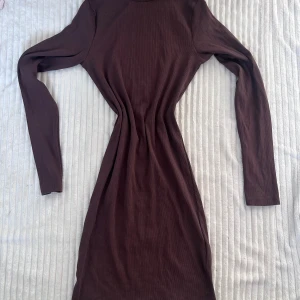 Brun ribbad långärmad klänning från Bik Bok - Säljerw en brun ribbad klänning från Bik Bok i storlek S. Klänningen har lång ärm, polokrage och är figurnära i modellen. Perfekt för dig som gillar en enkel men stilren look.