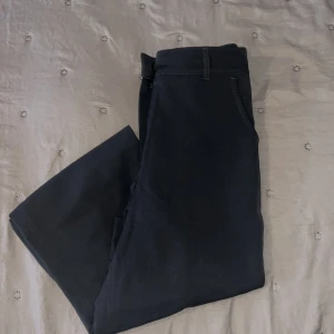 Gråa kostymbyxor med raka ben - Säljer ett par gråa kostymbyxor med klassisk passform och raka ben. Byxorna har hällor för bälte och diskreta sidfickor. Perfekta för en stilren och enkel look.