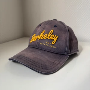 Berkeley - Säljer ett par Berkeley keps i marinblå men den har tappat sin färg men funkar perfekt och trycket är fin som ny! Kan säljas tillsammans med min andra keps på min profil.  Vill helst sälja båda kepsen tillsammans